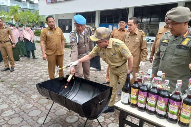 Pj Wali Kota Banda Aceh Bakri Siddiq memimpin pemusnahan barang bukti 36 botol miras hasil sitaan Satpol PP dan WH Kota Banda Aceh, Selasa (27/9). Foto: Humas Banda Aceh