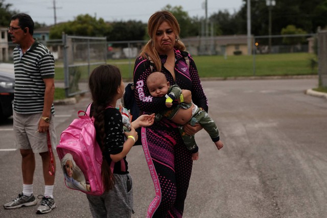 Seorang wanita menggendong bayi memasuki tempat penampungan bagi para pengungsi, saat Badai Ian berputar ke arah negara bagian, di sekolah dasar Lockhart di Tampa, Florida, AS, Selasa (27/9/2022). Foto: Shannon Stapleton/REUTERS