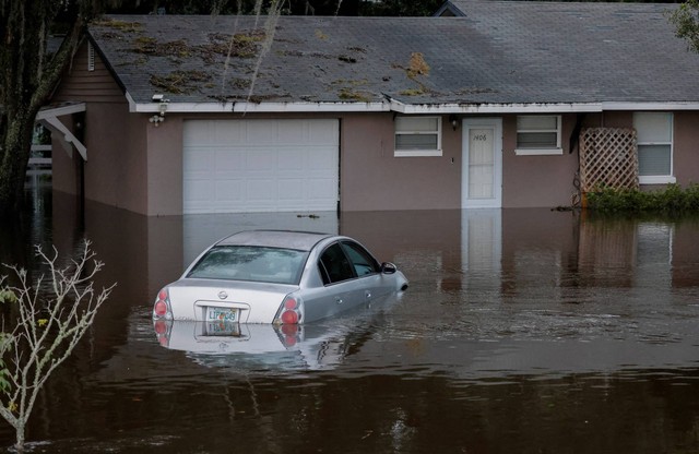 Sebuah mobil dan rumah yang sebagian terendam setelah badai Ian menyebabkan kerusakan luas dan banjir di Kissimmee, Florida, AS, Kamis (29/9/2022). Foto: Joe Skipper/Reuters