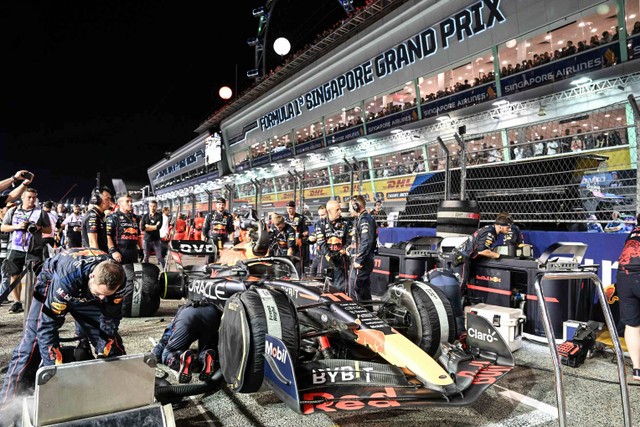 Pekerja kru pit mempersiapkan mobil pembalap Meksiko Red Bull Racing Sergio Perez sebelum balapan malam F1 Singapura Grand Prix di Sirkuit Jalan Marina Bay di Singapura, Minggu (2/10/2022). Foto: Mohd RASFAN / AFP