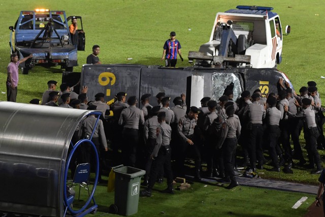 Polisi mengevakuasi mobil yang rusak akibat kerusuhan di lapangan Stadion Kanjuruhan, Malang, Jawa Timur, Minggu (2/10/2022). Foto: Zabur Karuru/Antara Foto