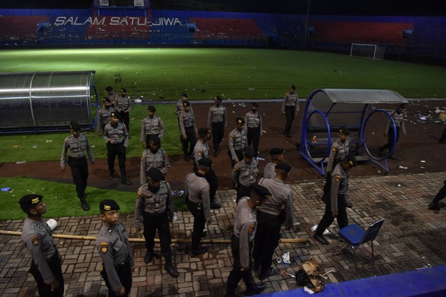 Sejumlah polisi melintas di pinggir lapangan Stadion Kanjuruhan, Malang, Jawa Timur, Minggu (2/10/2022). Foto: Zabur Karuru/Antara Foto