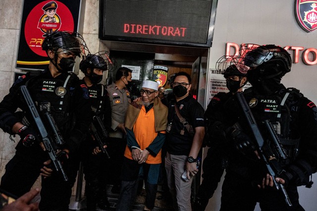 Personel Korps Brimob melakukan pengamanan tersangka mantan pimpinan Khilafatul Muslimin Abdul Qadir Baraja (tengah) menuju mobil tahanan di Polda Metro Jaya, Jakarta, Senin (3/10/2022). Foto: Galih Pradipta/ANTARA FOTO