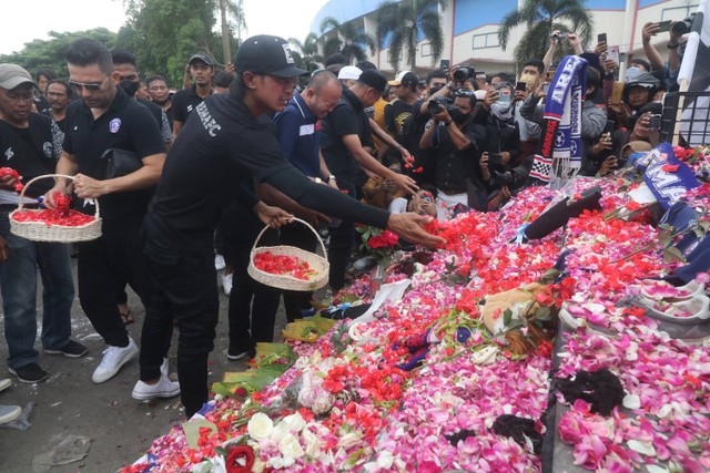 Sejumlah pemain dan official Arema FC menaburkan bunga di depan patung Singa Tegar kawasan Stadion Kanjuruhan, Malang, Jawa Timur, Senin (3/10/2022).  Foto: Prasetia Fauzani/ANTARA FOTO