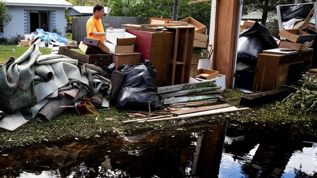 Warga terdampak badai Ian mulai membersihkan rumah mereka di kawasan Pantai New Smyrna, Florida, Senin (3/10/2022). Foto: Jim Watson/AFP