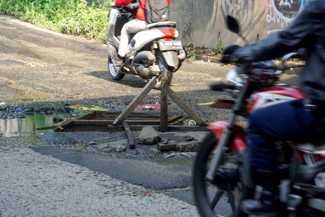 Sejumlah pengendara saat melintas di dekat jalan berlubang di Jalan K.H Noer Ali, Bekasi, Jawa Barat, Selasa (4/10/2022). Foto: Iqbal Firdaus/kumparan