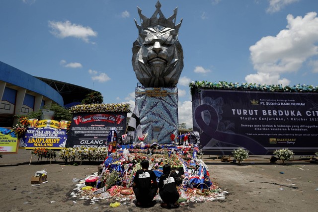 Warga berdoa di sekitar Patung Singa Stadion Kanjuruhan, Malang, Jawa Timur, setelah insiden kerusuhan, Selasa (4/10/2022). Foto: Willy Kurniawan/REUTERS