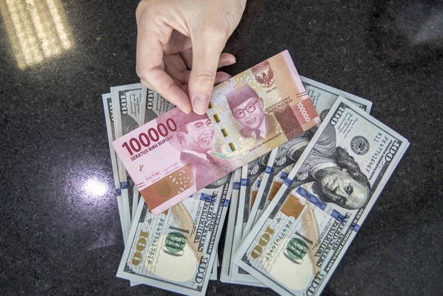 Petugas menunjukan uang pecahan Rupiah dan dolar AS di gerai penukaran mata uang asing VIP (Valuta Inti Prima) Money Changer, Jakarta, Selasa (4/10/2022). Foto: Muhammad Adimaja/Antara Foto