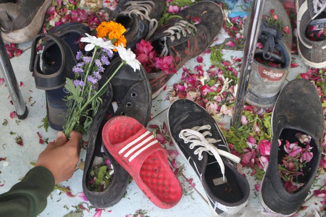 Suporter Arema FC (Aremania) meletakkan bunga di atas alas kaki para korban yang tertinggal di depan pintu tribun 11 Stadion Kanjuruhan, Malang, Jawa Timur, Selasa (4/10/2022).  Foto: Ari Bowo Sucipto/ANTARA FOTO