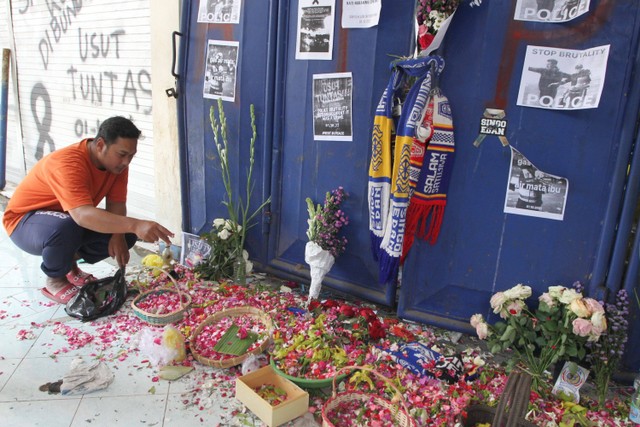 Seorang suporter Arema FC (Aremania) menaburkan bunga di depan pintu tribun 13 Stadion Kanjuruhan, Malang, Jawa Timur, Selasa (4/10/2022).  Foto: Ari Bowo Sucipto/ANTARA FOTO