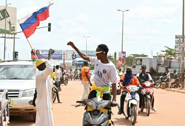Seorang pengunjuk rasa mengibarkan bendera Rusia saat ia bergabung dengan demonstrasi di Ouagadougou, Burkina Faso, Selasa (4/10).  Foto: Issouf SANOGO / AFP