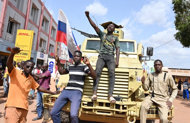 Seorang pengunjuk rasa mengibarkan bendera Rusia saat ia bergabung dengan demonstrasi di Ouagadougou, Burkina Faso, Selasa (4/10).  Foto: Issouf SANOGO / AFP