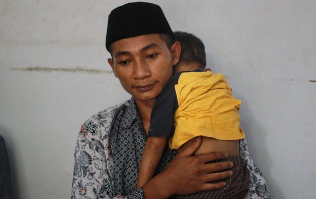 Andik Harianto menggendong anaknya Gean Putra Harianto yang selamat di tragedi Stadion Kanjuruhan. Foto/Rubianto
