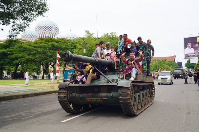 Anak-anak dan orang tuanya naik tank TNI. Foto: Korem 011