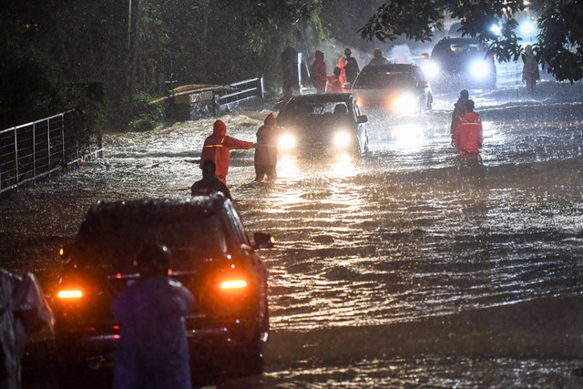 Petugas Penanganan Prasarana dan Sarana Umum (PPSU) mengimbau pengendara mobil saat menerjang banjir di kawasan Jeruk Purut, Jakarta Selatan, Kamis (6/10/2022). Foto: M Risyal Hidayat/Antara Foto 