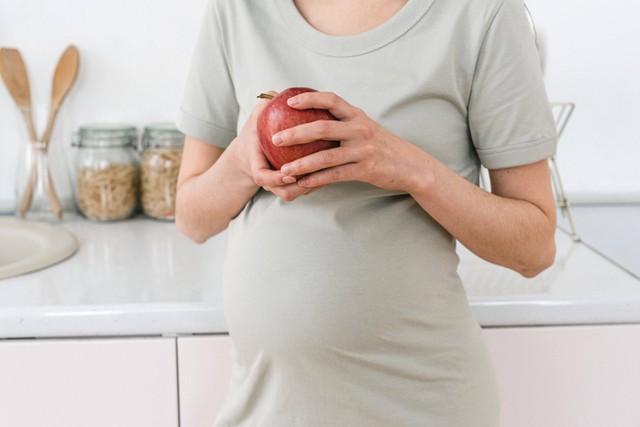 Ilustrasi ibu hamil yang mengonsumsi buah apel. Foto: Pexels