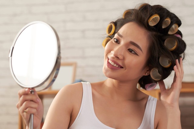 Ilustrasi perempuan mengeriting rambut dengan metode heatless curls.
 Foto: Shutterstock