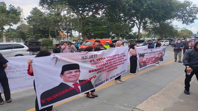 Mahasiswa membentangkan spanduk dengan foto Sekdaprov Riau, SF Hariyanto, saat unjuk rasa di depan Kantor Kejati Riau. (Foto: Istimewa)