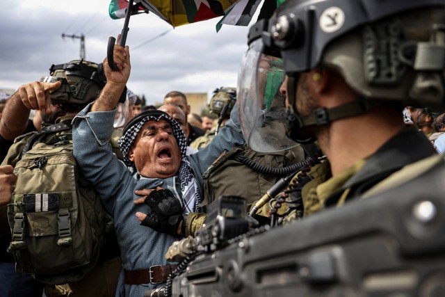Seorang demonstran Palestina menghadapi pasukan keamanan Israel saat protes terhadap pengambilalihan tanah Palestina oleh Israel di desa Kfar Qaddum di Tepi Barat, pada Jumat (7/10/2022). Foto: Ronaldo Schemidt/AFP