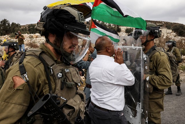 Seorang demonstran Palestina menghadapi pasukan keamanan Israel saat protes terhadap pengambilalihan tanah Palestina oleh Israel di desa Kfar Qaddum di Tepi Barat, pada Jumat (7/10/2022). Foto: Ronaldo Schemidt/AFP