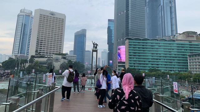 Pengunjung CFD berfoto di anjungan halte TransJakarta Bundaran HI pada Minggu (9/10/2022). Foto: Luthfi Humam/kumparan