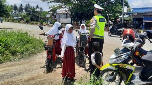 Polisi memberi teguran ke pelajar SD yang berkendara sepeda listrik di jalan raya di Pasangkayu, Sulawesi Barat. Foto: Dok. Polres Pasangkayu