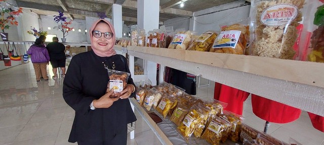 Seorang ibu tengah memegang produknya di showroom UMKM