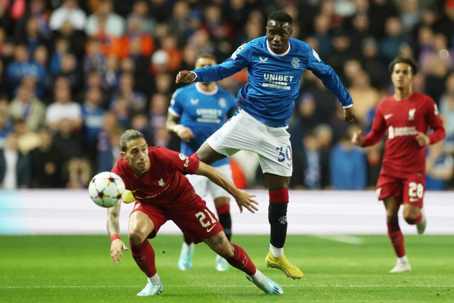 Pemain Liverpool Kostas Tsimikas berebut bola dengan pemain Rangers Fashion Sakala pada pertandingan Grup A Liga Champions di Ibrox Stadium, Glasgow, Skotlandia, Inggris. Foto: Lee Smith/REUTERS