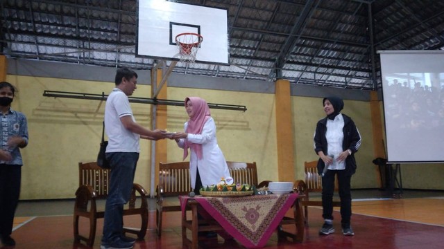 Pemberian potongan tumpeng oleh Kepala SMAN 8 Malang kepada Coach tim basket. Foto / Feni Yusnia