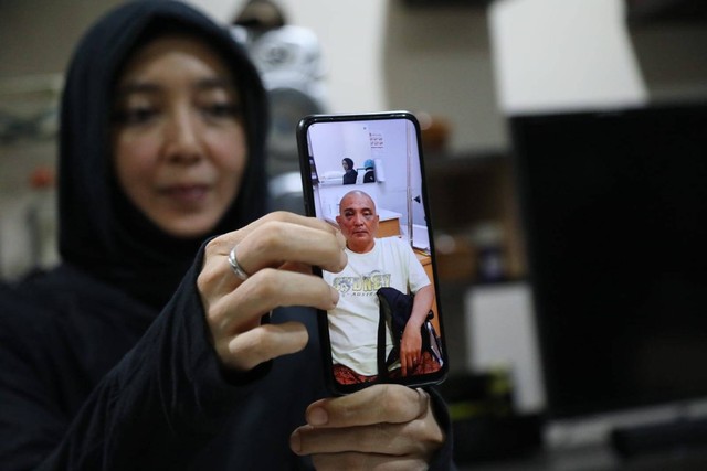 Istri John Jaiz Muhammad, Puti Intan Ageyani Boudewijn, menunjukkan foto suaminya yang luka-luka. Foto: Aditia Noviansyah/kumparan