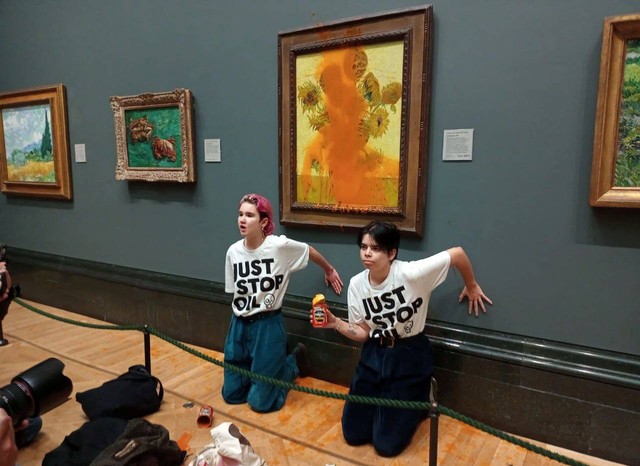 Aktivis "Just Stop Oil" menempelkan tangan ke dinding setelah melemparkan sup ke lukisan van Gogh "Sunflowers" di Galeri Nasional di London, Inggris, Jumat (14/10/2022). Foto: Just Stop Oil via Reuters