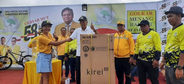 Bupati Sintang Jarot Winarno menyerahkan doorprize pada peserta jalan sehat HUT Partai Golkar ke-58. (Foto: Yusrizal/Hi! Pontianak)