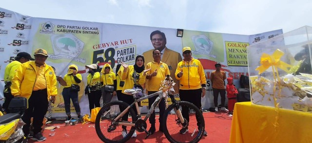 Ketua Fraksi Partai Golkar DPRD Sintang, Toni menyerahkan hadiah sepeda pada pesera jalan sehat HUT Golkar ke -58. (Foto: Yusrizal/Hi! Pontianak)