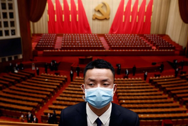 Seorang personel keamanan, mengenakan masker wajah setelah wabah penyakit virus corona (COVID-19), berjaga-jaga di akhir upacara pembukaan Kongres Nasional ke-20 Partai Komunis Tiongkok, di Aula Besar Rakyat di Beijing, China, Minggu (16/10/2022). Foto: Thomas Peter/REUTERS