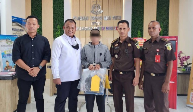 Penyidik Ditreskrimum Polda Aceh menyerahkan tersangka kasus pembakaran bendera merah putih berinisial RA (tengah) ke Kejaksaan Negeri Bireuen. Foto: Dok. Polisi
