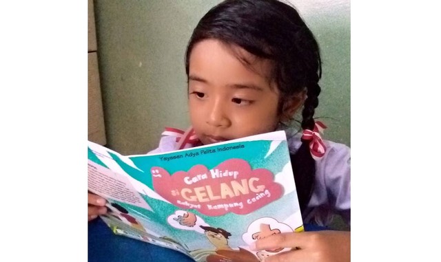 Seorang anak membaca buku petunjuk mengatasi cacingan untuk mencegah stunting - IST