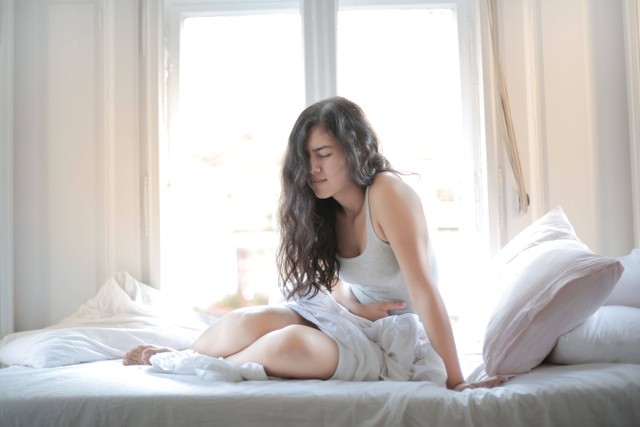 Kram perut saat menstruasi bisa ditangani dengan posisi tidur untuk meredakan nyeri haid. Foto: Pexels.com