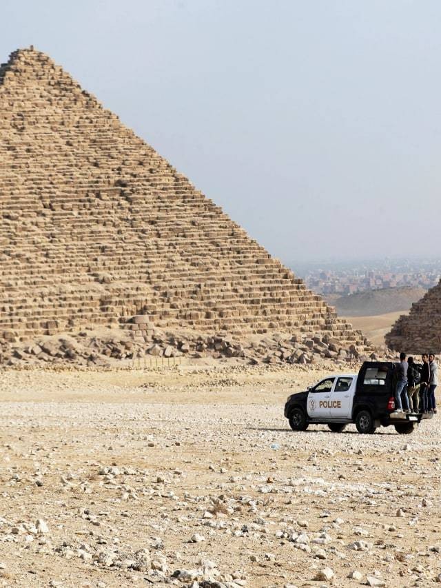 Sebuah mobil polisi melintas di dekat Piramida Agung, dataran tinggi piramida Giza di Giza, Mesir. Foto: Mohamed Abd El Ghany/Reuters