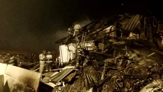 Petugas pemadam kebakaran bekerja di lokasi kecelakaan pesawat menabrak bangunan perumahan di kota Irkutsk, Rusia, Minggu (23/10/2022). Foto: Kementerian Darurat Rusia/Handout via REUTERS 