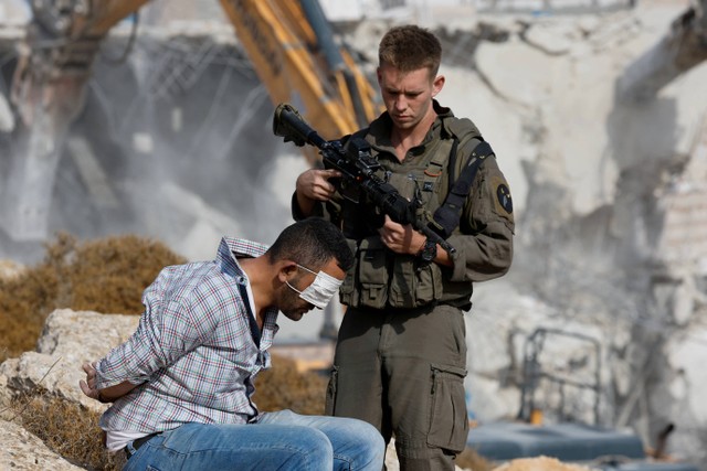 Warga Palestina terlibat bentrok dengan pasukan Israel di Hebron, Tepi Barat yang diduduki Israel, Selasa (25/10/2022). Foto: Mussa Qawasma/Reuters