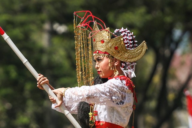 Seorang peserta mengibarkan bendera merah putih saat karnaval budaya di Taman Mini Indonesia Indah, Jakarta, Jumat (28/10/2022). Foto: Asprilla Dwi Adha/Antara Foto