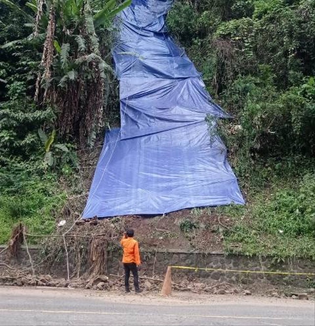 Petugas BPBD Sumedang memasang terpal di titik longsor yang terjadi di Jalan Raya Cadas Pangeran. Foto: Diskominfosanditik Sumedang