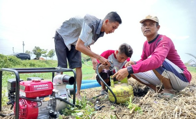 Darma (49) petani bawang merah di Kabupaten Brebes, Jawa Tengah dibantu anak- anaknya menyiapkan pompa air dengan bahan bakas gas LPG 3 Kg untuk mengaliri areal persawahannya di Desa Limbangan Kulon, Kecamatan Brebes, Jumat (4/11/2022).