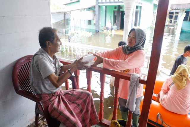 Relawan Mak Ganjar Sumatera Utara membagikan paket makanan untuk warga yang terdampak banjir di Langkat menggunakan perahu karet. Foto: Dok. Istimewa