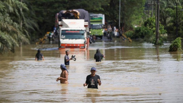 Warga menerobos banjir di jalan Banda Aceh-Medan, kawasan Aceh Tamiang, Ahad (6/11). Foto: Suparta/acehkini