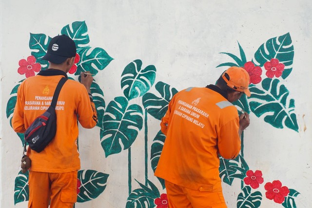 Petugas pasukan oranye wilayah Cipinang Melayu membuat mural motif bunga di kolong jalan tol Becakayu, Jatiwaringin, Jakarta Timur pada Selasa (8/11). Foto: Iqbal Firdaus/kumparan