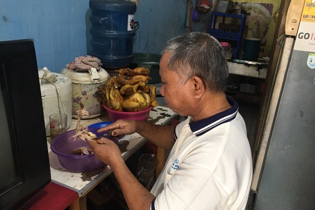 Djunaedi sedang membuat pesanan makanan di warung pecel lelenya di Depok. Foto: Ainun Nabila/kumparan