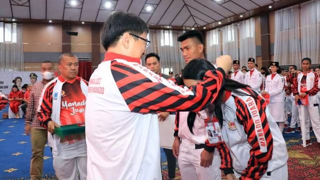 Wali Kota Manado, Andrei Angouw saat mengalungkan tanda atlet pada pelepasan kontingen Pekan Olahraga Provinsi Sulawesi Utara.