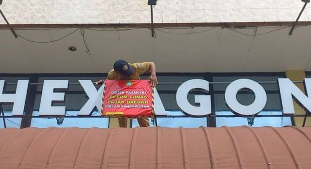 Petugas memasang stiker 'Tak Bayar Pajak' di papan nama Hexagon di Wisma Nusantara. Foto: Dok Pemkot Pontianak