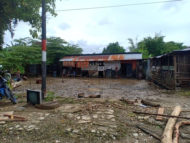 Rumah membersihkan material banjir pasca air merendam rumahnya. (Foto Humas Polda Papua) 